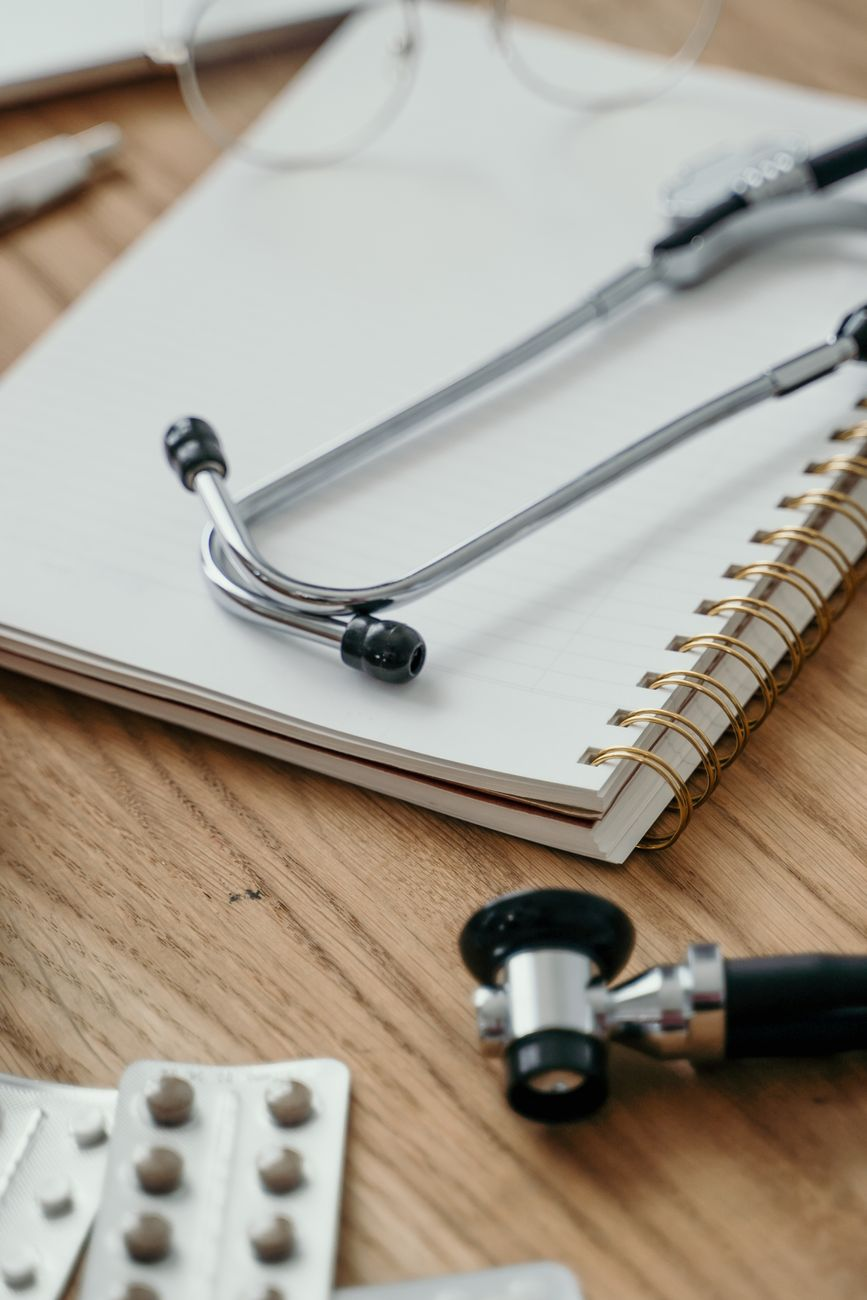 stethoscope notebook and medicines on doctors office desk